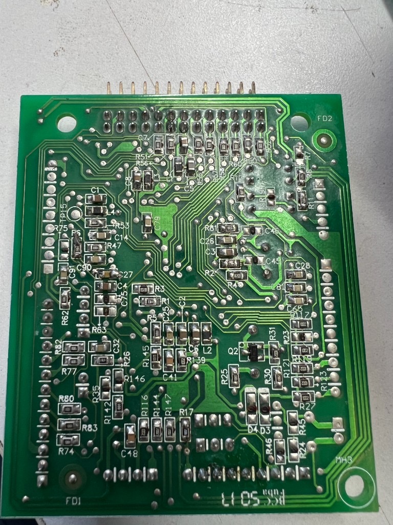 Close-up of a green printed circuit board densely packed with surface-mount components and copper traces